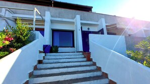 A staircase leading to a building entrance with a blue door and a small window.