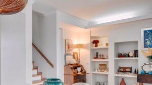A dining area with a wooden table and chairs, a staircase, and a shelving unit with decorative items. - Rochinha’s house with fabulous views over the bay of funchal (Funchal)