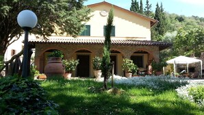 A two-story building with a stone facade, green shutters, and a tiled roof.