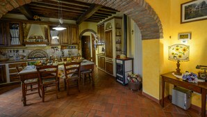 A rustic kitchen with a brick archway, wooden furniture, and a dining table set for four.