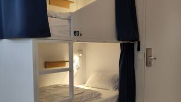 Ein Stockbett mit Schublade, einer Nachttischlampe und einer Tür mit Griff.
