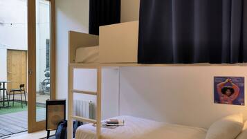A bunk bed with a lower bunk, a small table, and a chair.