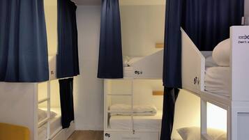 Habitación tipo dormitorio con literas, cortinas y un escritorio pequeño.