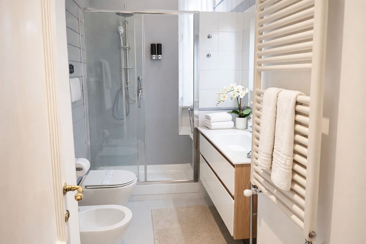 Une salle de bain moderne avec une douche à parois de verre, des toilettes, un lavabo avec un porte-serviettes et un miroir.