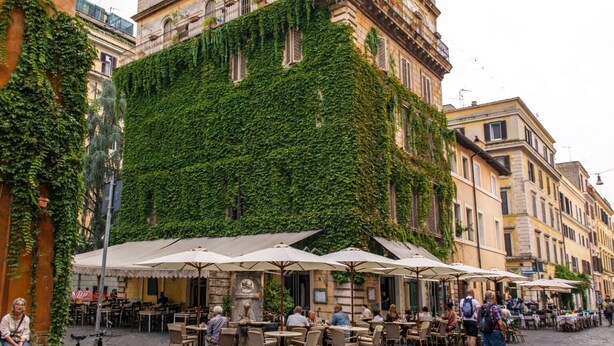 An outdoor café with tables and umbrellas, surrounded by buildings with green ivy. - Lux comfort privacy in the center of Rome, shared by a group of 10 friends (Roma)