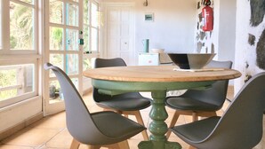 A dining area with a round table, four chairs, and a fire extinguisher on the wall. - CASA AURA sunshine over the sea (Hermigua la gomera)