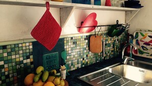 A kitchen with a tiled backsplash, a fruit bowl, a sink, and various kitchen utensils and containers on shelves. - CASA AURA sunshine over the sea (Hermigua la gomera)