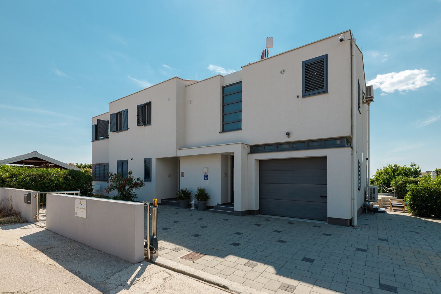 Ein modernes, zweistöckiges Gebäude mit Garage, überdachter Eingangsparte und befestigter Auffahrt.