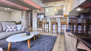 Un salon moderne avec un canapé, une table basse et un coin cuisine équipé de tabourets de bar.