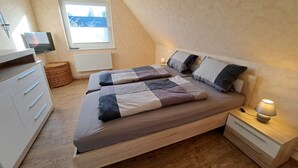 Une chambre avec deux lits, une télévision, une lampe et une fenêtre.