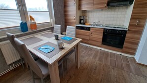 Une cuisine moderne avec des meubles en bois, un four encastré et une fenêtre donnant sur un paysage enneigé.