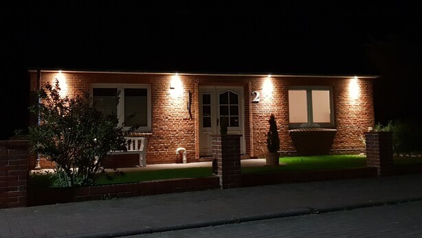 Une maison en briques avec le chiffre « 2 » sur la façade, une porte d’entrée et un petit porche.