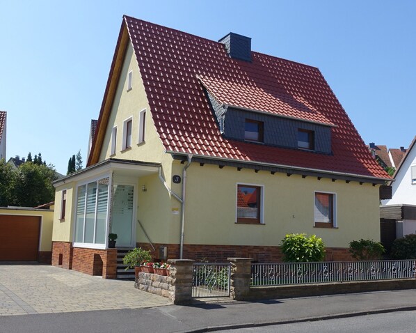 A two-story house with a red-tiled roof, a front porch, and a brick entrance. - Quiet, fully furnished *** apartment in the adventure land Werra-Meißner (Eschwege)