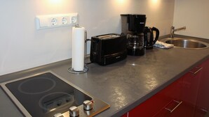 Eine Küchenzeile mit eingebautem Herd, einer Kaffeemaschine, einem Toaster und einem Spülbecken.