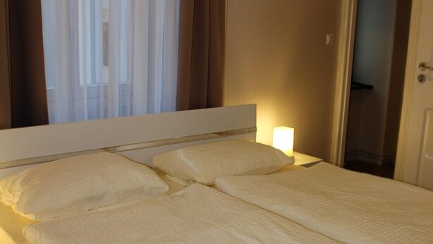 Ein ordentlich bezogenes Bett mit weißen Laken in einem Hotelzimmer.