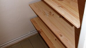 Ein Raumeck mit einem Holzregal an einer weißen Wand.