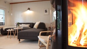 Ein gemütliches Wohnzimmer mit einer Couch, einem kleinen Tisch, einem Sessel und einem Kamin.