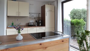 Eine moderne Küche mit Holzarbeitsplatten, einem eingebauten Herd und einem großen Fenster mit Blick auf Grünfläche.