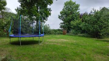 Enjoy a peaceful backyard with a trampoline, lush green grass, and serene surroundings.