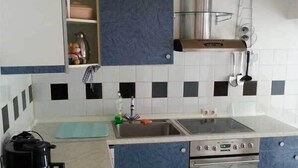 Una cucina compatta con piano cottura, lavello e pensili.