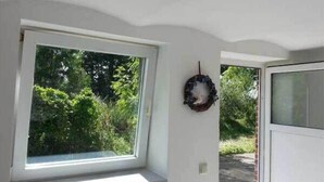 Una stanza con un'ampia finestra, una porta e una ghirlanda appesa al muro.