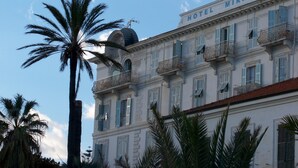 Um hotel com estilo arquitetônico clássico, apresentando várias varandas e uma placa bem visível com a inscrição 
