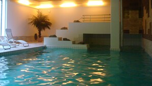 Ein Innenpool mit einer eingelassenen Sitzgruppe, einer Treppe und einem Blumentopf.