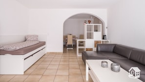 A compact living space with a bed, a sofa, a small table, and a white cabinet.