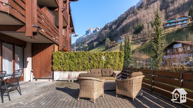 Ein Holzbau mit Balkon, Korbmöbeln und Bergblick.
