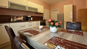 A modern kitchen with white cabinets, a wooden countertop, and a dining area with a table set for two. - New Feriewohnung in the heart of the valley with stunning view to Roßtrappe, **** (Thale)