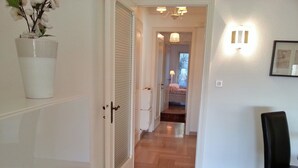 A hallway with a white door, a potted plant, a black chair, and a light fixture on the wall. - 4 *, BEACH / EVENTS, direct access to the beach, pool, garage, park. (Cannes)