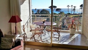 A balcony with a table and chairs, a potted plant, and a view of the ocean. - 4 *, BEACH / EVENTS, direct access to the beach, pool, garage, park. (Cannes)