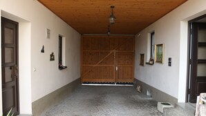 A corridor with a wooden ceiling, a large wooden door at the end, and a cobblestone floor. - Brunow vacation apartment "At home in nature" (Neundorf)