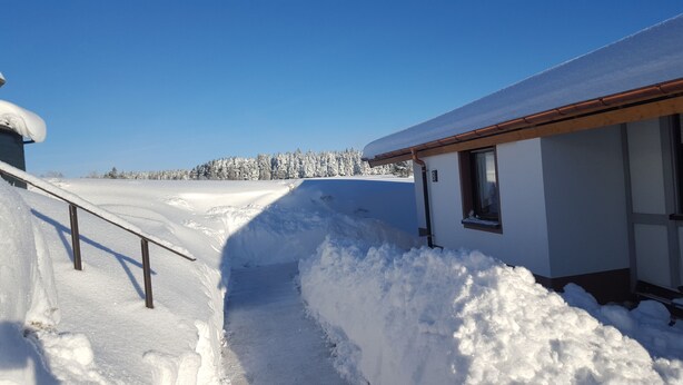 Paisaje nevado con un edificio que tiene techo de madera y una ventana con el número 8.