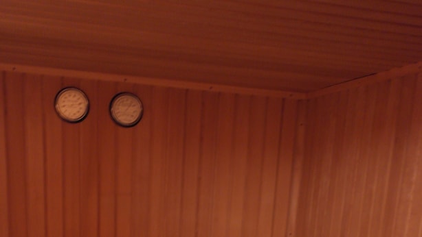 Una sauna de madera con bancos y un banco con estructura metálica.