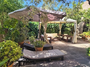 A covered outdoor seating area with wicker furniture and potted plants. - Romantic house with garden and mountain views (Cala San Vicente)