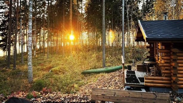 Uma cabana com varanda, rodeada por uma floresta.