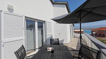 A balcony with a table, chairs, and a large umbrella.