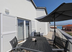 A balcony with a table, chairs, and a large umbrella.