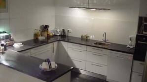 A modern kitchen with white cabinets, a black countertop, and a stainless steel sink.