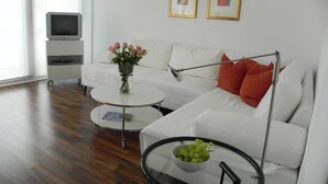 Un salon moderne avec un canapé blanc, une table basse en verre et un meuble pour la télévision.