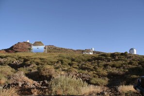 Un paysage vallonné parsemé de plusieurs structures blanches en forme de dôme, qui pourraient être des observatoires, par temps clair.