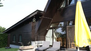 Una casa moderna con techo inclinado, ventanas grandes y un paraguas amarillo.