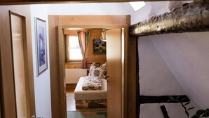 Un pasillo estrecho que da a un dormitorio con cama, una ventana con cortinas y una planta.