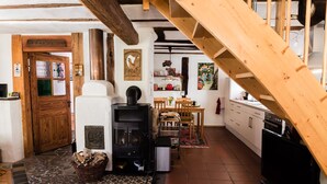 Un interior rústico con una escalera de madera, chimenea, comedor y cocina.