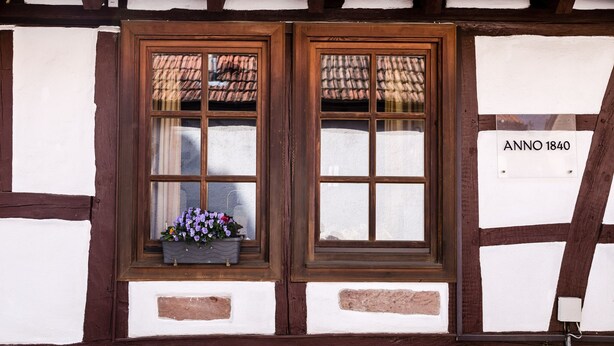 Un edificio tradicional con entramado de madera y dos ventanas, una con una caja de flores.