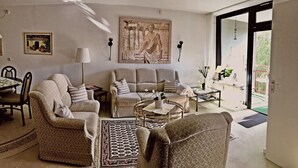 Una sala de estar con sofá, sillones, una mesa de centro y un comedor con sillas y una mesa.
