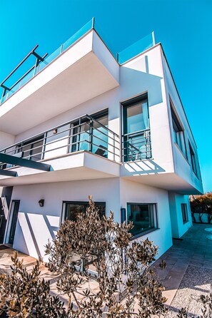 A modern multi-story building with balconies, large windows, and a clear sky. - CASA DO MAR - HOUSE BY THE SEA - (Areia Branca/ Ortsteil Casal Labrusque)