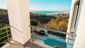 A balcony with a view of the ocean and a pool.