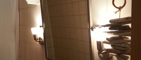 A bathroom with a tiled wall, a mirror, a toilet, a glass shelf, and a towel rack.